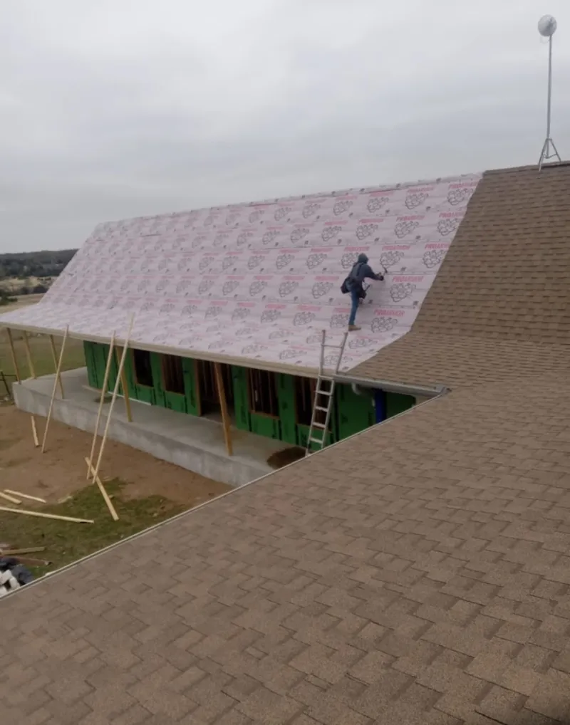 Worker preparing underlayment for a metal roof installation in Herculaneum